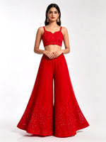 Front view of a vibrant scarlet wide-leg sharara, featuring intricate red paisley embroidery and delicate white beadwork along the hem, set against a pure white background.
