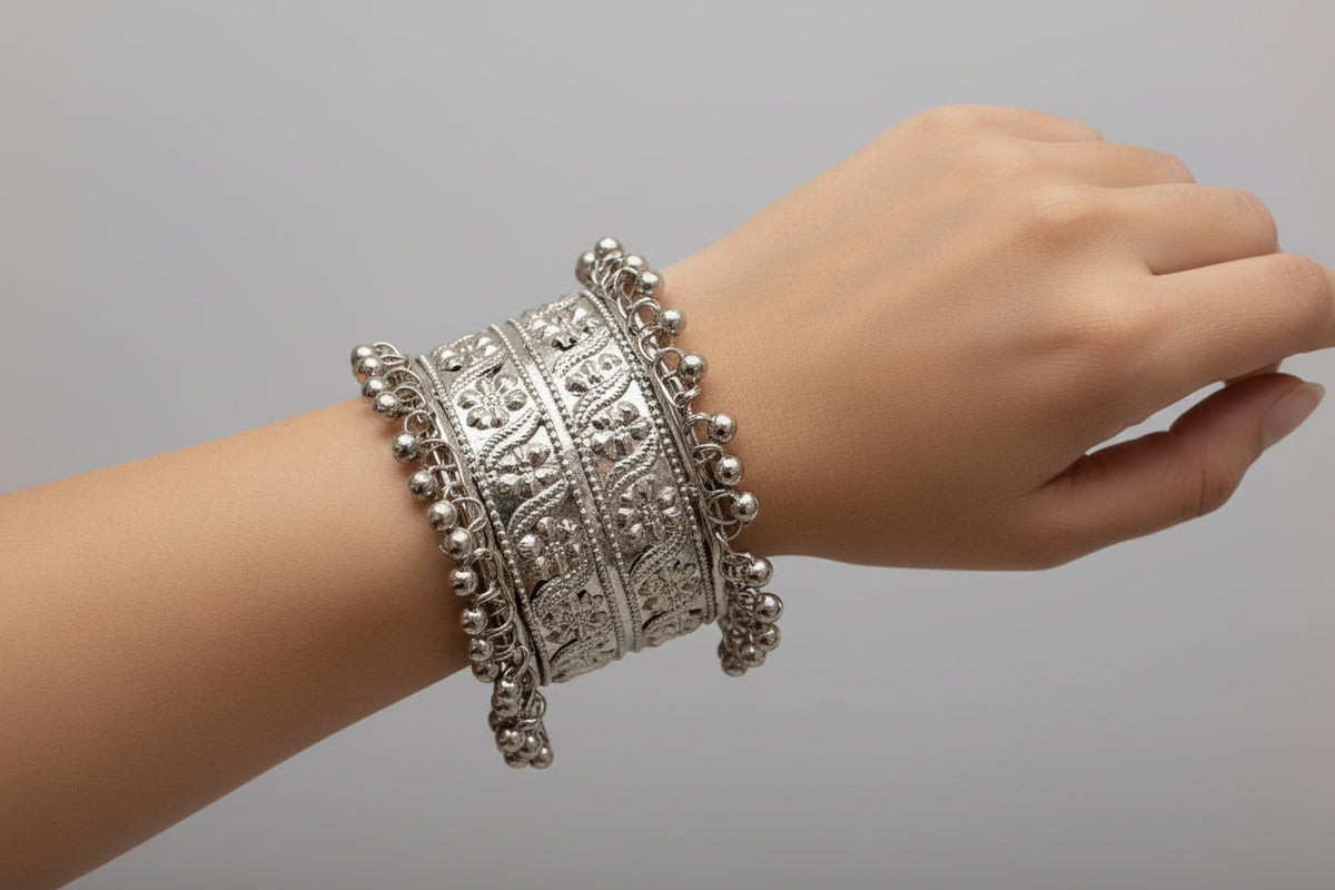 Silver bracelet with intricate design on a wrist against a gray background