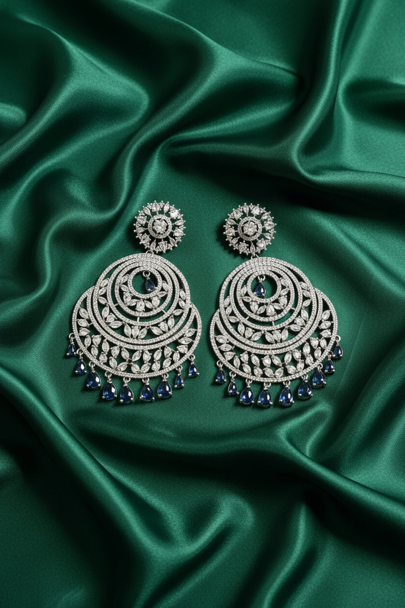 Silver earrings with blue stones on a green velvet stand