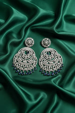 Silver earrings with blue stones on a green velvet stand