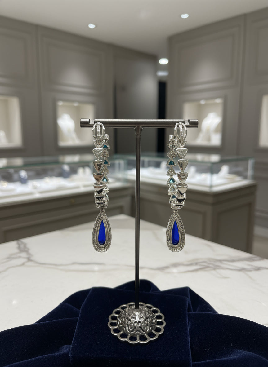 Silver earrings with blue stones on a stand in a jewelry store setting