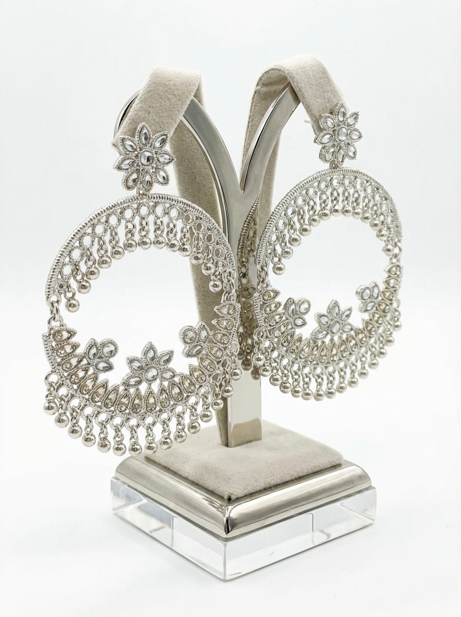 Silver jewellery stand with intricate designs on a white background