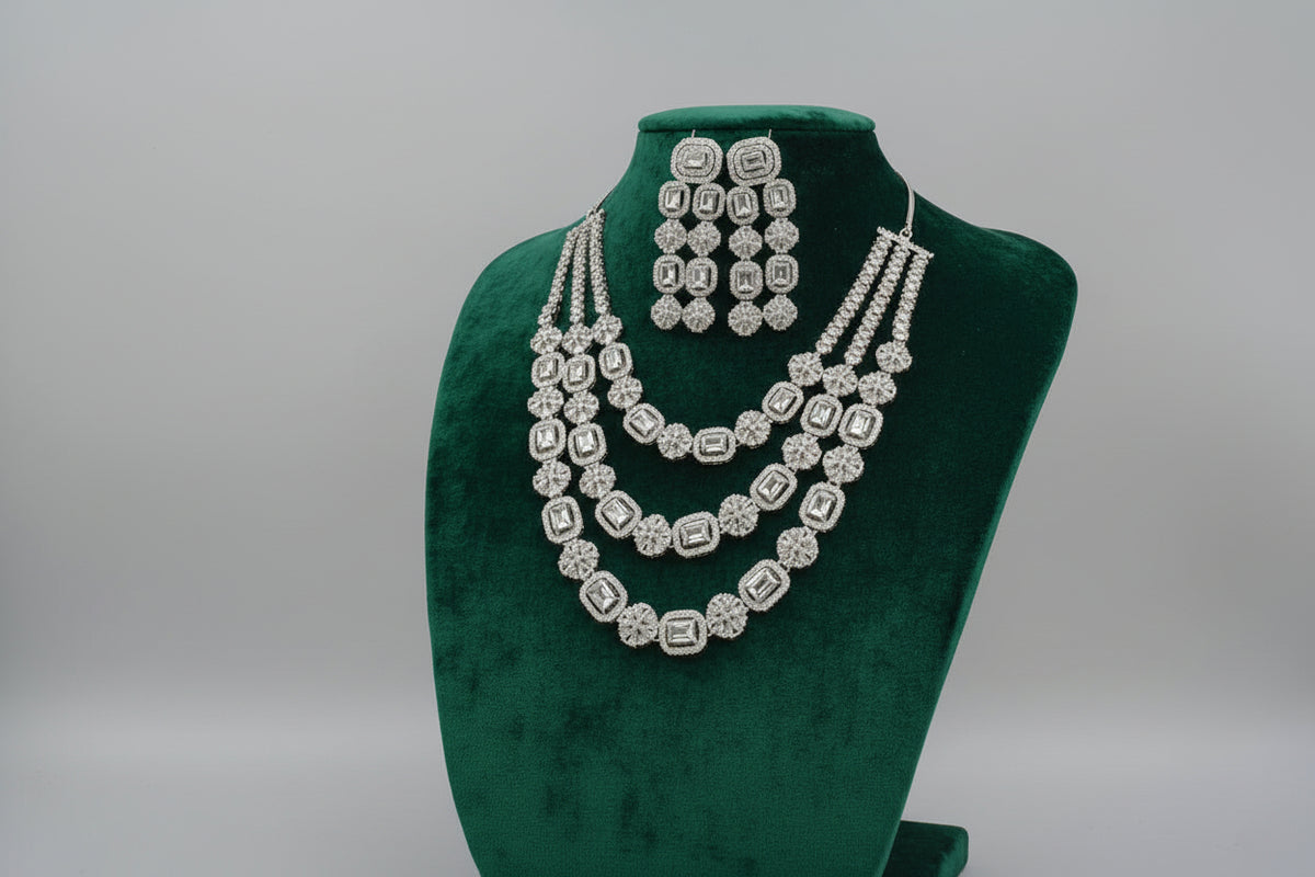 Silver jewelry set including necklace and earrings on a black mannequin.