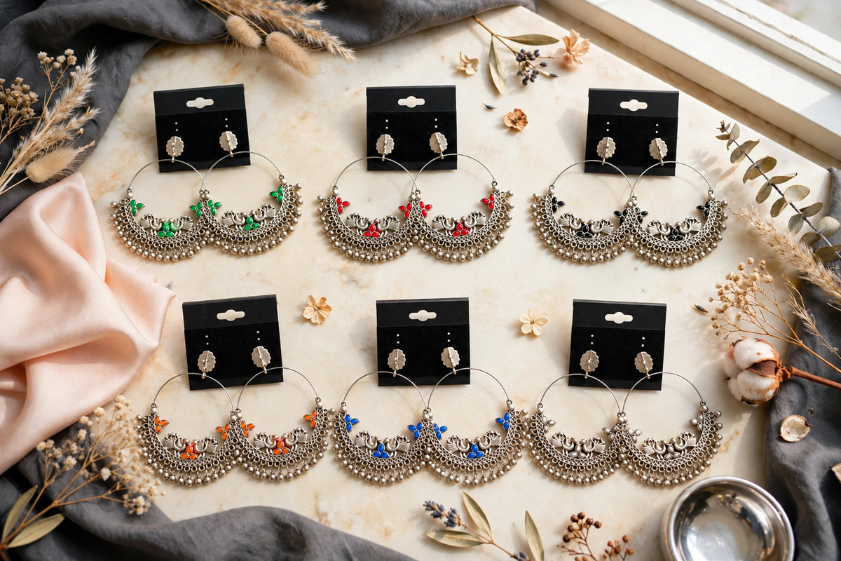 Six pairs of oxidised-look peacock chandbali earrings with ghungroo fringe, shown in green, red, black, orange, blue and white