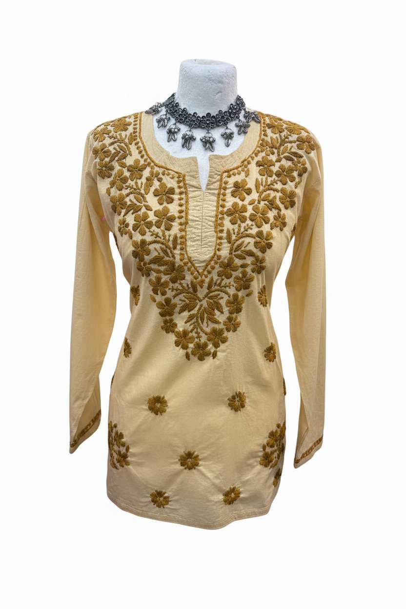 Creamy beige cotton short kurti featuring intricate dark yellow-brown floral embroidery along the neckline and scattered motifs across the front, displayed on a mannequin.