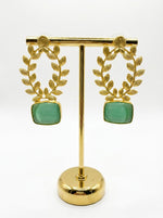 Statement earrings featuring an emerald green sugar stone with detailed floral carvings and golden accents.