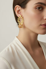 Statement earrings featuring an peach sugar stone with detailed floral carvings and golden accents.