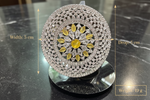A round pavé diamond jewelry stand or display piece shown on a dark marble surface, with measurement arrows and text indicating a diameter of 5 cm, drop of 5 cm, and weight of 19 g. The center features a yellow floral motif surrounded by clear stones.