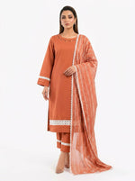 A full-length studio shot of a model wearing a three-piece terracotta plain cotton shalwar kameez suit from Famaza Couture. Features a solid terracotta straight-cut kurta with fine decorative detailing along the round neckline, matching trousers with intricate white lace panels and horizontal pintuck pleats at the hem, and a draped sheer patterned dupatta with delicate lace borders, all styled against a seamless white background.
