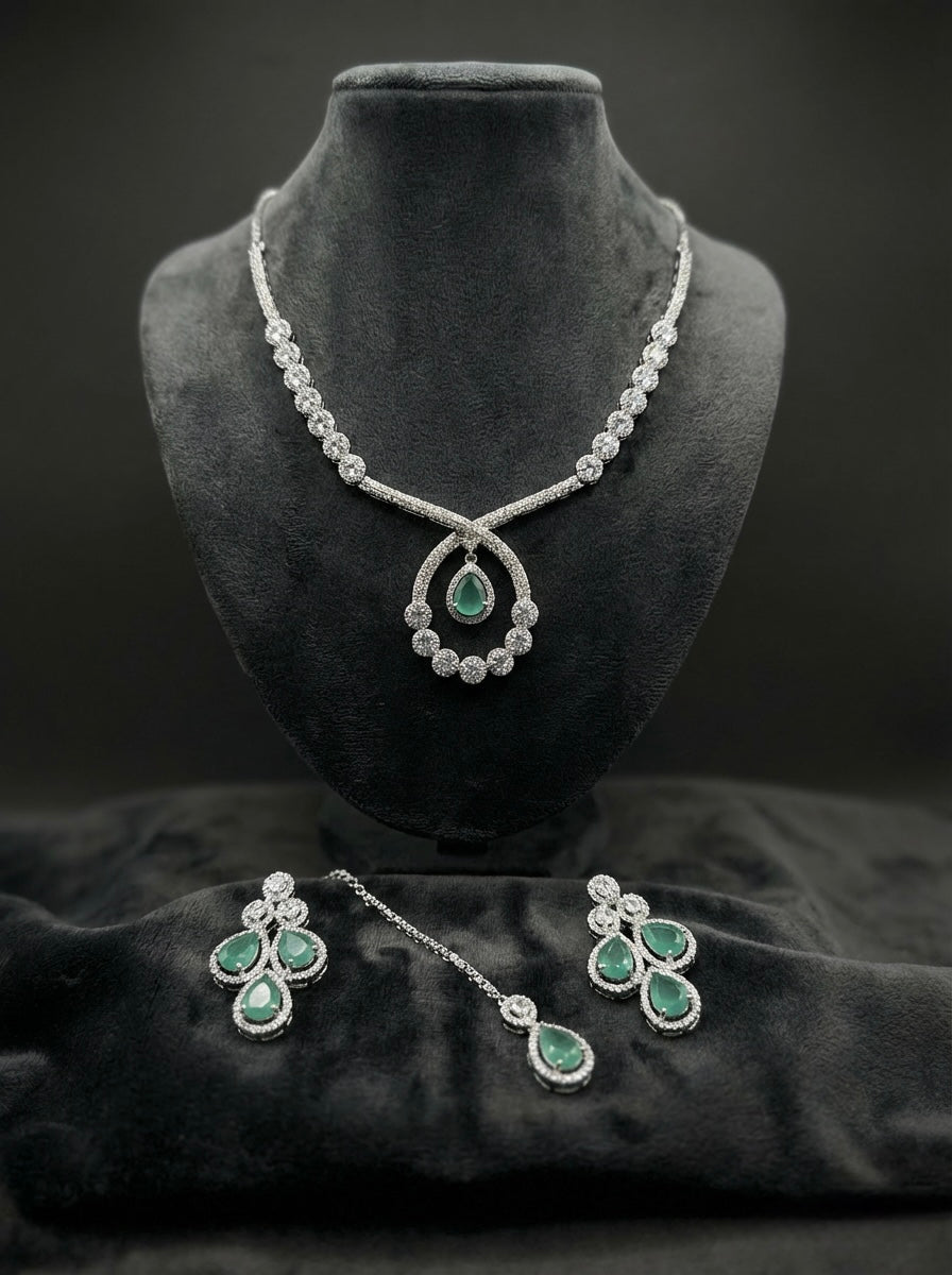 The American diamonds bridal jewellery set including necklace, earrings and maang tikka with Turquoise colour central cubic zirconia stones.