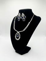 The American diamonds bridal jewellery set including necklace, earrings and maang tikka with purple colour central cubic zirconia stones.