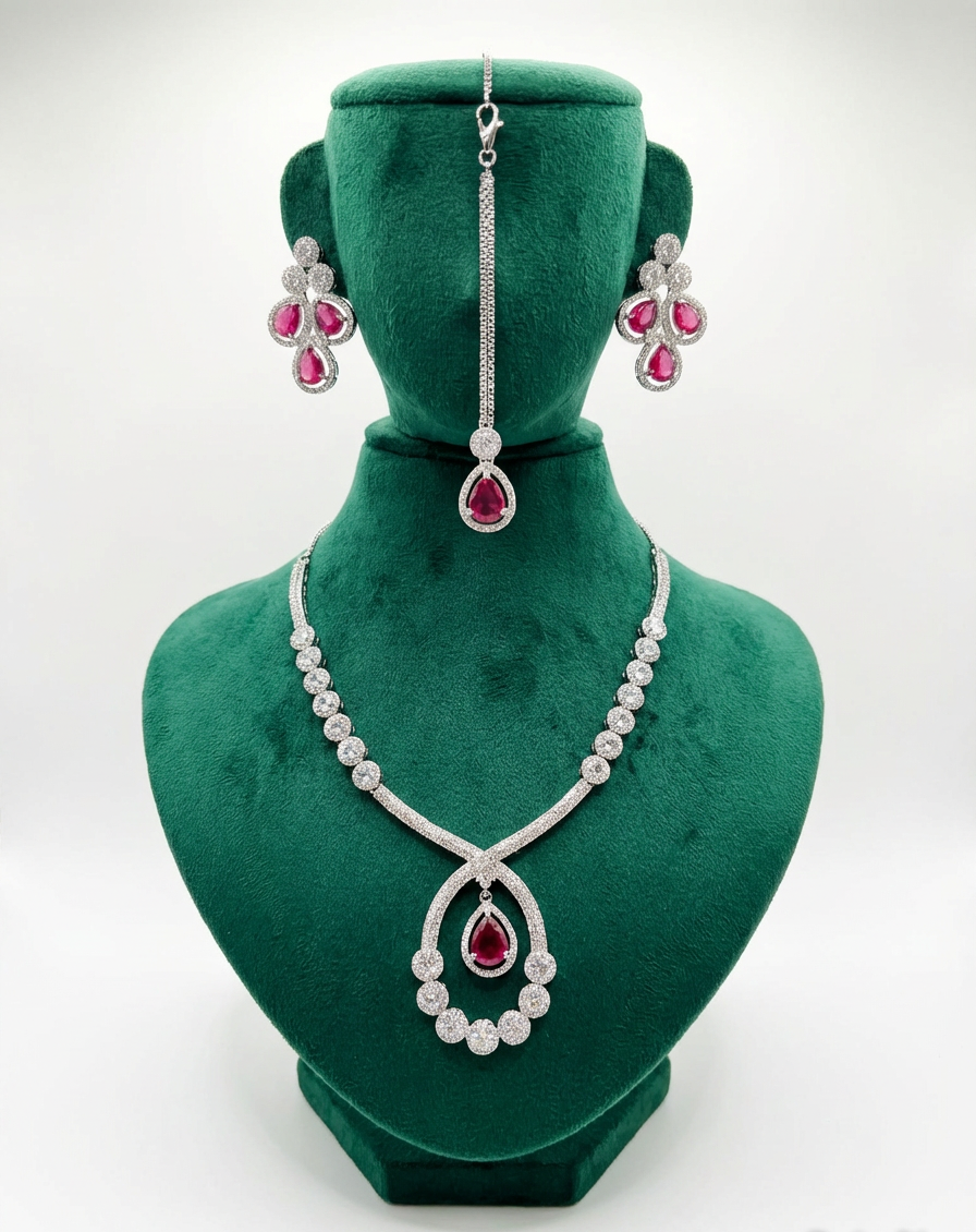 The American diamonds bridal jewellery set including necklace, earrings and maang tikka with ruby colour central cubic zirconia stones.