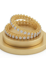 Close-up lifestyle shot of a model wearing two stackable hexagonal gold-plated bangles, featuring brilliant-cut baguette crystals and micro-pavé detailing against a white fabric background.