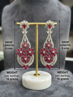 Long ruby and crystal floral statement earrings on a display stand with 8 cm drop length and 16-gram weight annotations.