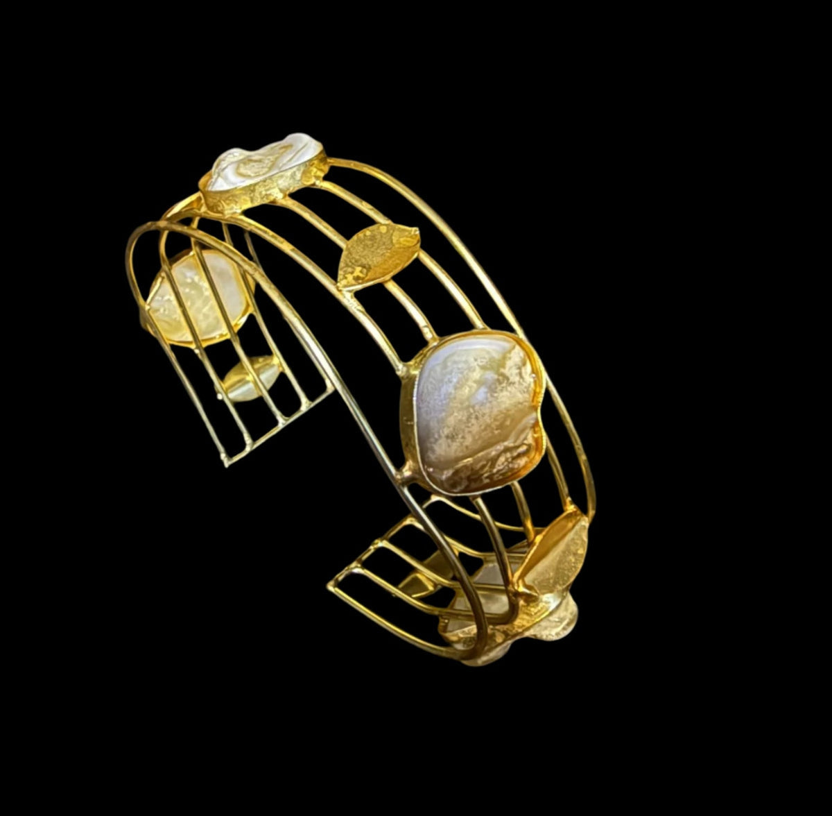 Gold bracelet with leaf-shaped stones on a black background