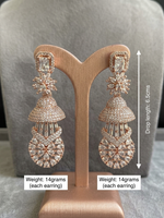 A pair of luxury rose gold multi-tier Jhumka chandelier earrings displayed on a matching rose gold T-bar stand, featuring an emerald-cut crystal top stud, a marquise floral star link, a micro-pave dome, and a lower teardrop lattice medallion.