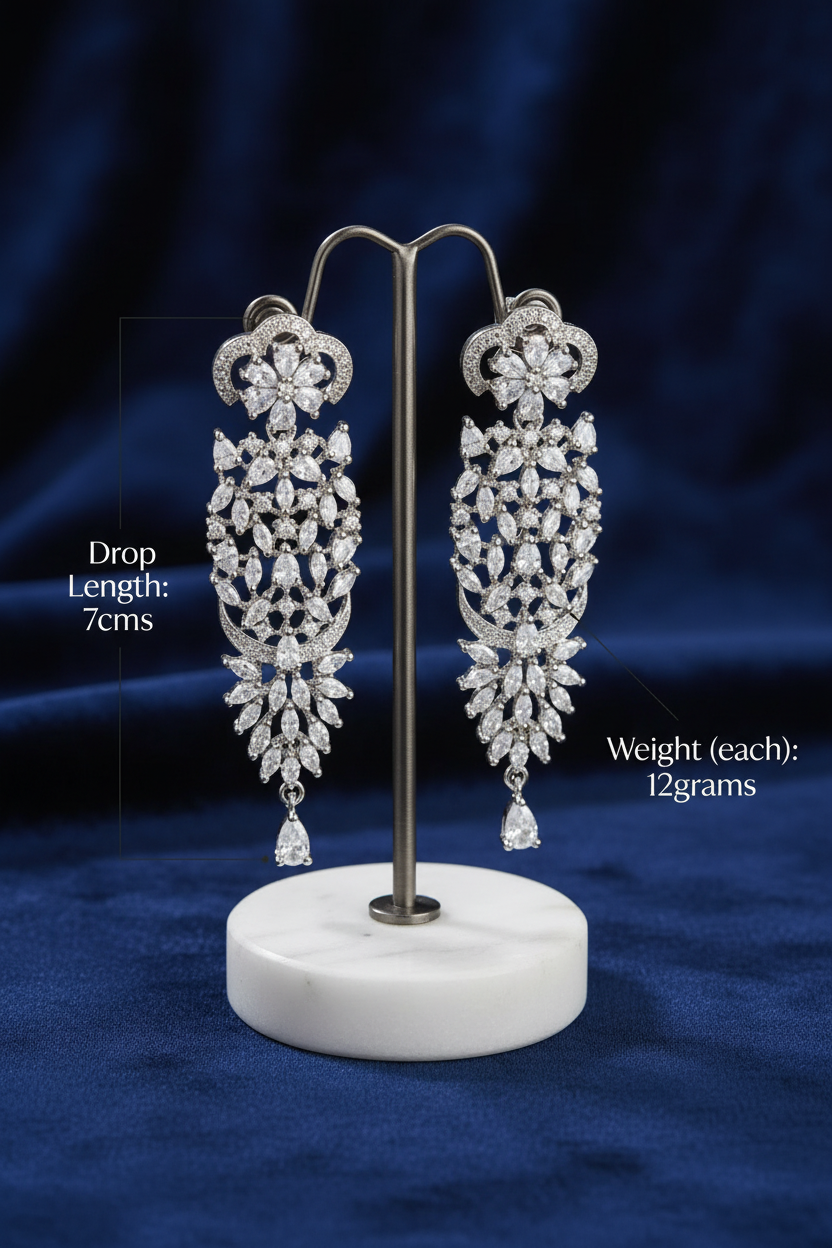 Elegant long silver statement earrings intricately set with brilliant marquise and teardrop cubic zirconia crystals, showcased on a luxury retail display stand in