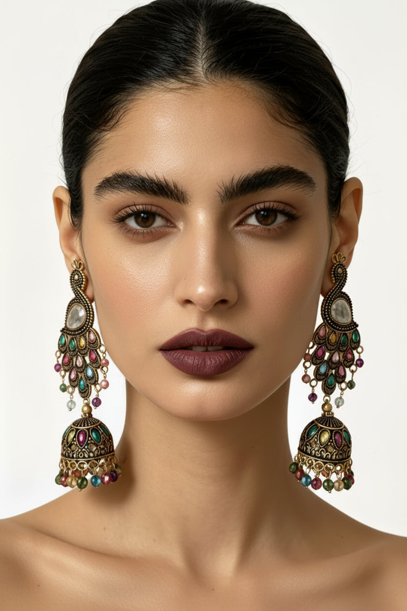 Close-up portrait of a model wearing The Imperial Peacock antique gold-plated multistone jhumka earrings, featuring a detailed peacock motif and a multi-colored beaded dome.