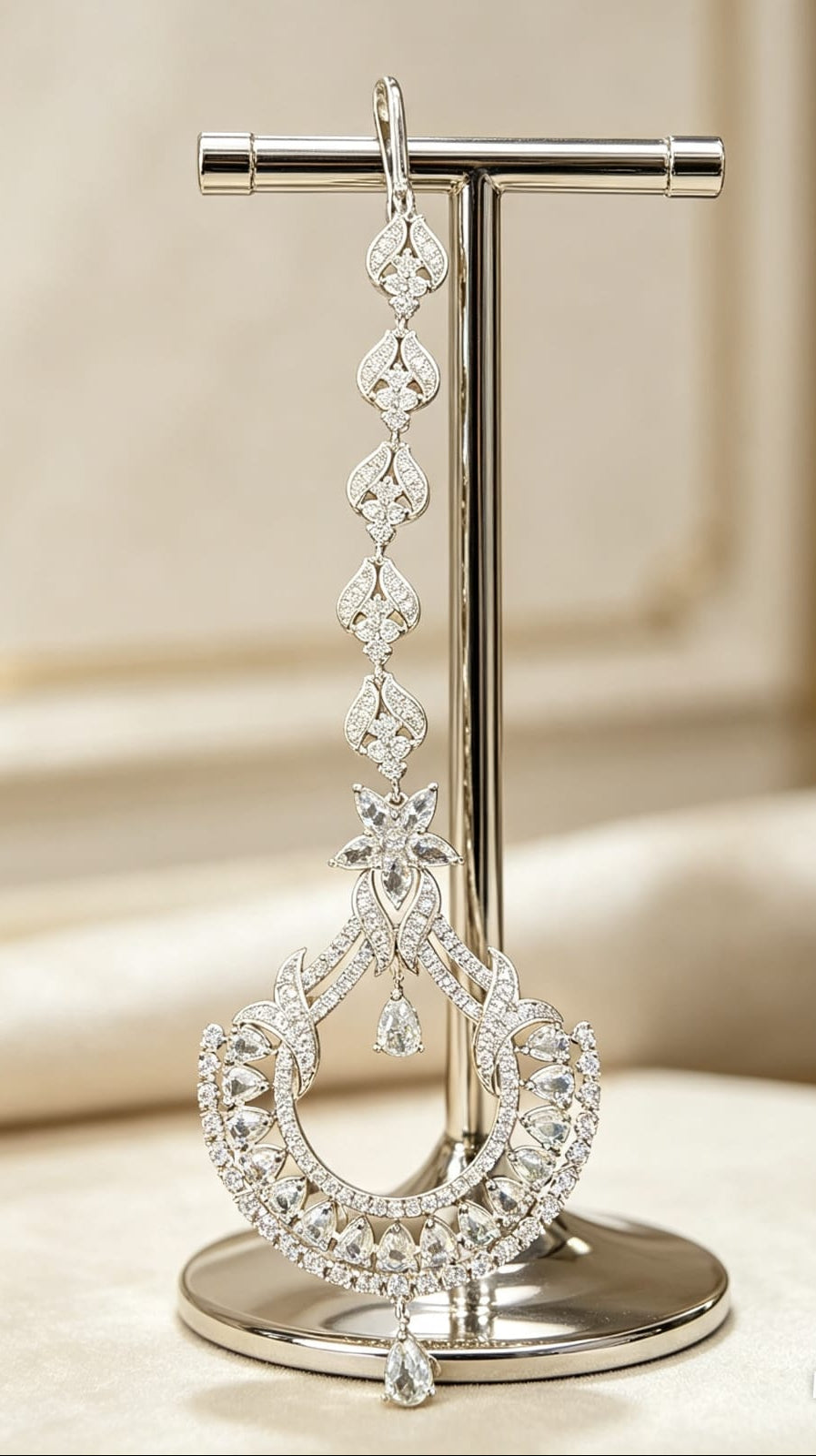 The Siya Extended Star & Crescent Luxe Cubic Zirconia Maang Tikka — silver-toned, cascading floral-teardrop links, star motif, pear & round cut CZ stones, long bridal forehead jewelry, Indian Pakistani wedding ornament displayed on stand.