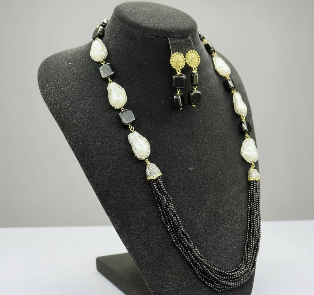 The black mannequin showcasing a Bollywood style black colour Mona Lisa stone and black colour nano crystal beaded Mala set, with white colours of baroque pearls and gold-tone accents. Party wear jewellery set.
