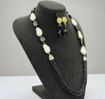 The black mannequin showcasing a Bollywood style black colour Mona Lisa stone and black colour nano crystal beaded Mala set, with white colours of baroque pearls and gold-tone accents. Party wear jewellery set.