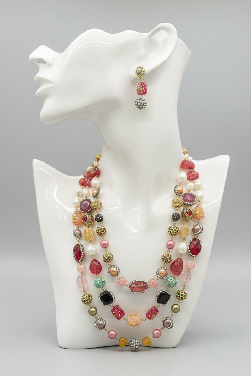 A gold-plated Kundan-studded and pearl-beaded handcrafted jewellery set, consisting of a necklace and earrings, displayed against a black background.