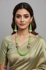 The luxurious Tanjore Art Meenakari apple green beaded Mala Set featuring a bridal pearl necklace with accompanying earrings, predominantly in gold and white colours with ornate designs.