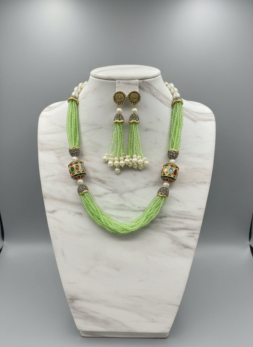 The luxurious Tanjore Art Meenakari apple green beaded Mala Set featuring a bridal pearl necklace with accompanying earrings, predominantly in gold and white colours with ornate designs. Party wear set.