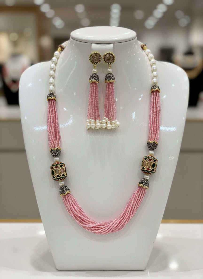 The luxurious Tanjore Art Meenakari pink beaded Mala Set featuring a bridal pearl necklace with accompanying earrings, predominantly in gold and white colours with ornate designs. Party wear set.