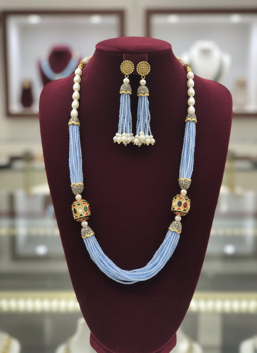 The luxurious Tanjore Art Meenakari sky blue beaded Mala Set featuring a bridal pearl necklace with accompanying earrings, predominantly in gold and white colours with ornate designs.