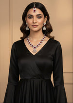 The mannequin showcasing a necklace set with ruby pink and white ad stones, accompanied by earrings and a maang tikka.