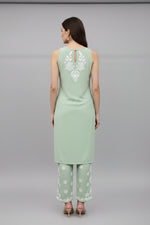 The rear view of Mint green colour sleeveless kurti and trousers with white hand embroidery is displayed next to each other on the hangers.