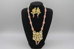 The traditional bridal necklace set displayed on a mannequin, featuring pink and gold colours with intricate detailing and pearl beads. Party wear jewellery set.