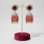 These earrings carries the redstone in the top stud and carrot red hangings underneath the Jhumkey dome and nano oxidised hanging in in the last.