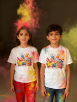 Two children wearing 'Happy Holi' t-shirts with colorful holi powder around them.