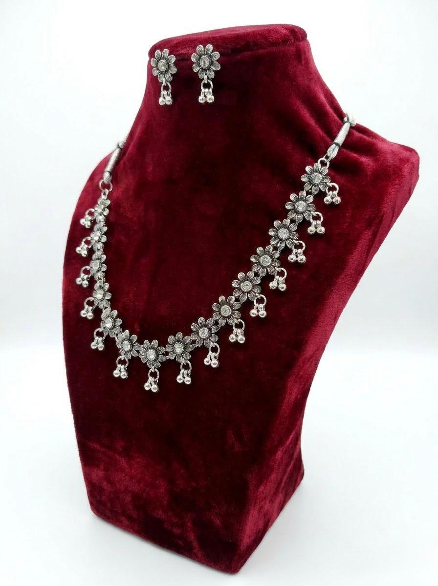 Oxidized silver sunflower-style jewelry set with clear crystal centers and triple-bead ghungroo drops displayed on a red velvet mannequin stand.