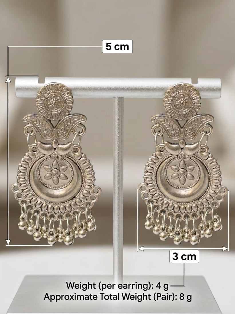 A pair of ornate silver-toned Indian-style dangle earrings displayed on a stand, with measurement labels showing 5 cm height, 3 cm width, and weight details of 4 g per earring.
