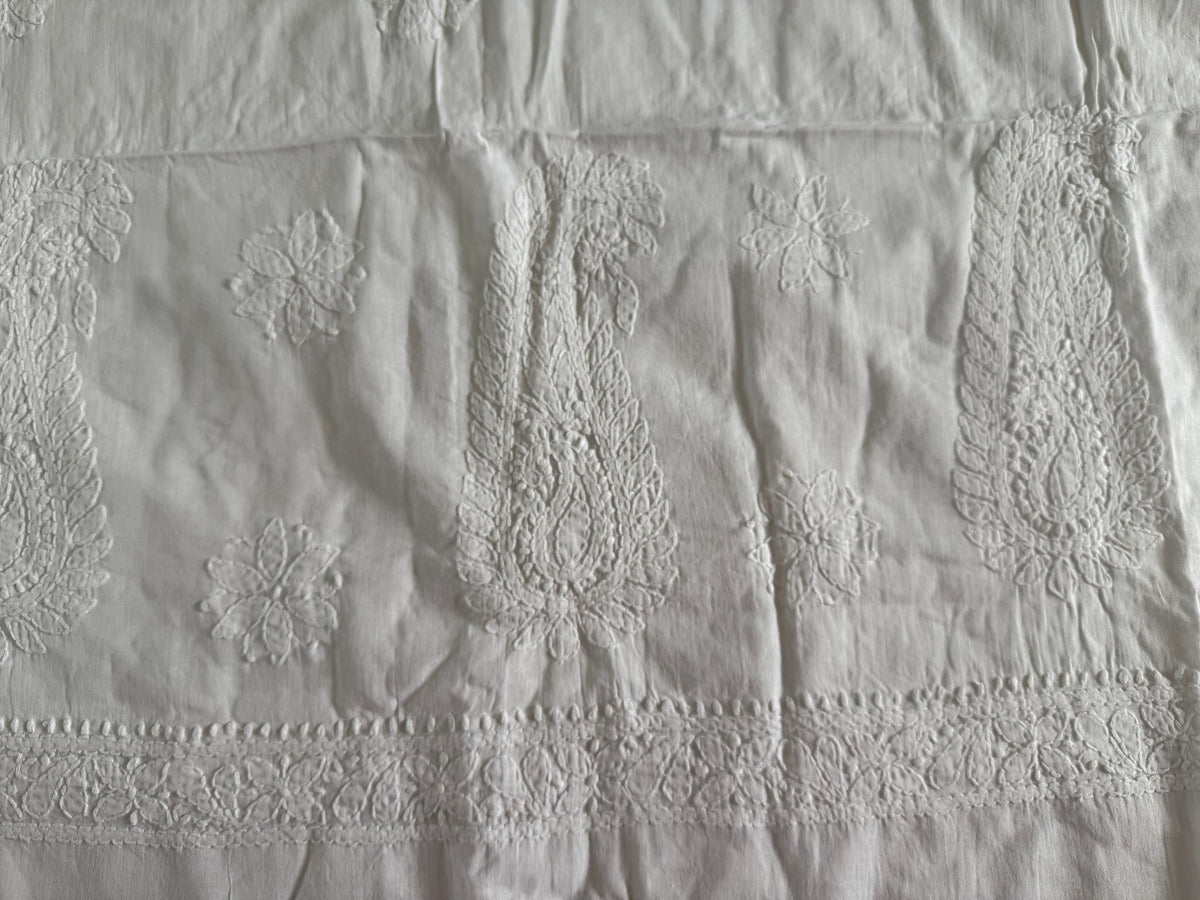 White embroidered cotton fabric with detailed floral and paisley patterns and a decorative border.