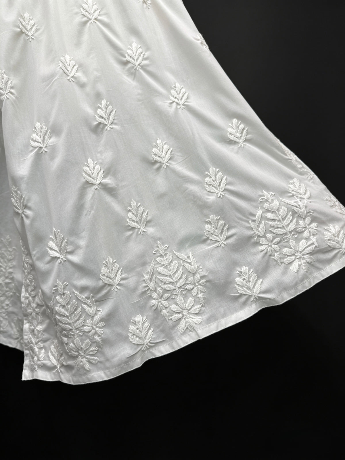 White embroidered fabric with floral patterns on a black background