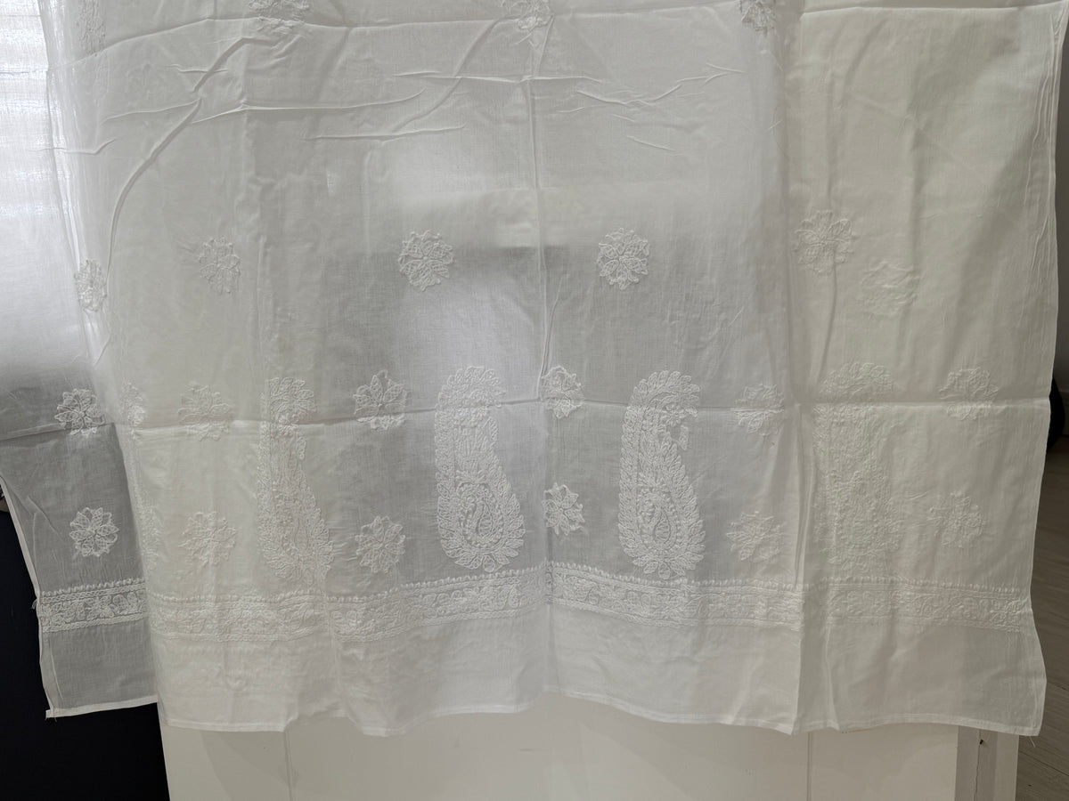 White sheer lace curtain panel with embroidered paisley and floral motifs, hanging on a white table.