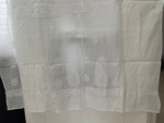 White sheer lace curtain panel with embroidered paisley and floral motifs, hanging on a white table.