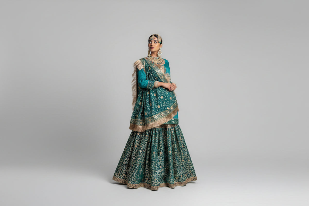 Woman in traditional green and gold bridal Gharara outfit standing on grass