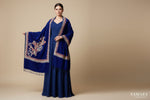 Woman wearing a blue embroidered outfit with a matching shawl on a beige background, featuring the brand 'Famaza Couture'.