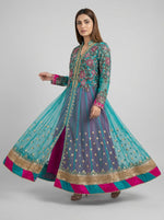 Woman wearing a colourful traditional outfit with a long, flowing design on a grey background