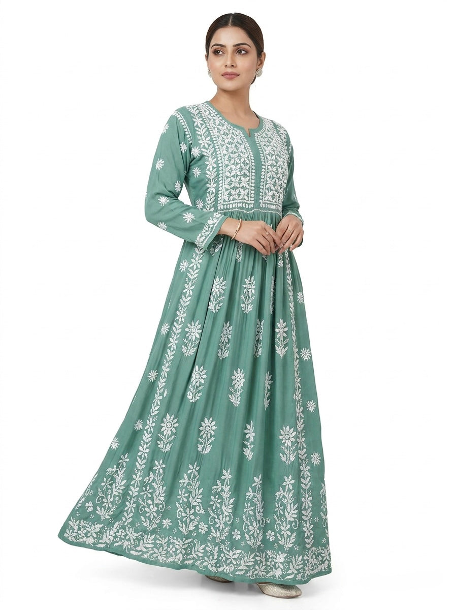 Woman wearing a green dress with white floral embroidery on a white background