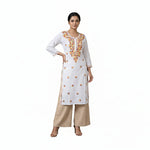 Woman wearing a white embroidered kurta with beige pants against a neutral background