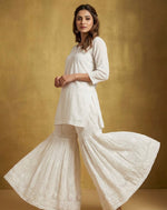 Woman wearing a whitetop and white flared hand embroidered gharara pants