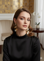 Woman wearing gold earrings with baroque pearls in an elegant indoor setting