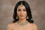Woman wearing traditional jewellery including a necklace, earrings, and a headpiece against a neutral background