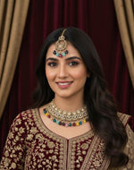 Woman wearing traditional jewelry and attire against a draped curtain background